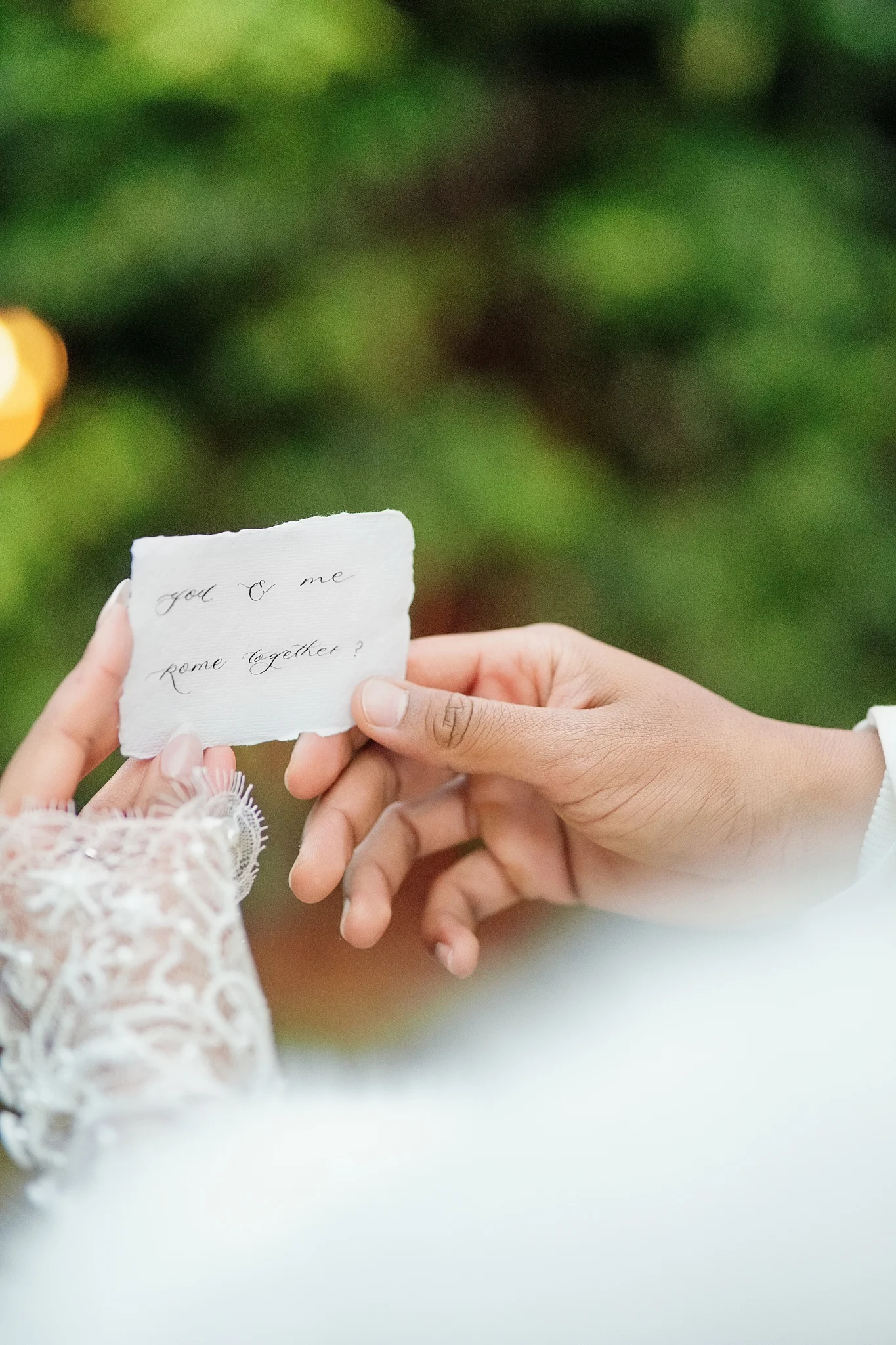 Two hands gently hold a small piece of paper with a handwritten message.