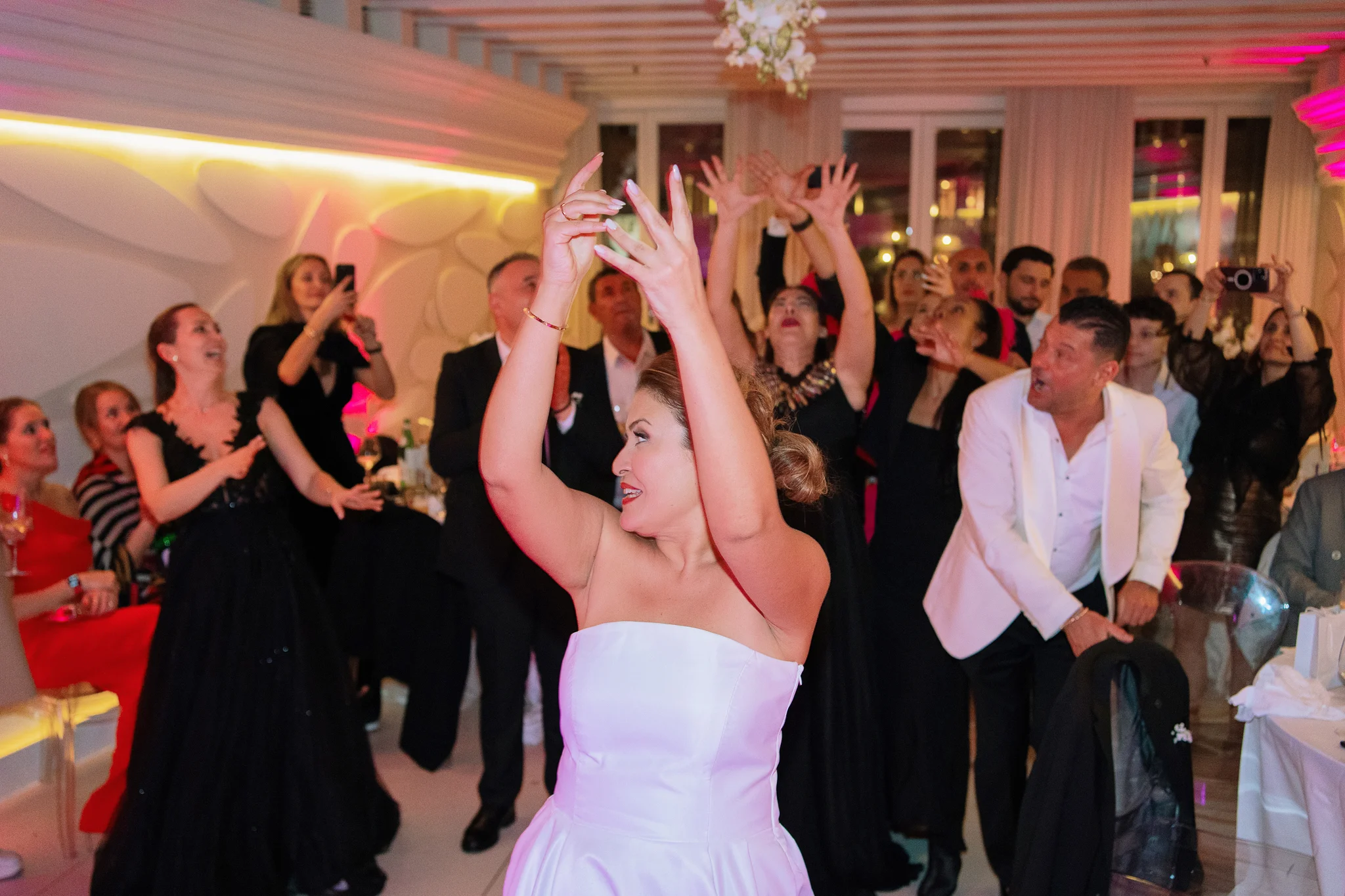 Bride joyfully flips her bouquet to eager guests, a classic shot to include in a wedding photo checklist.